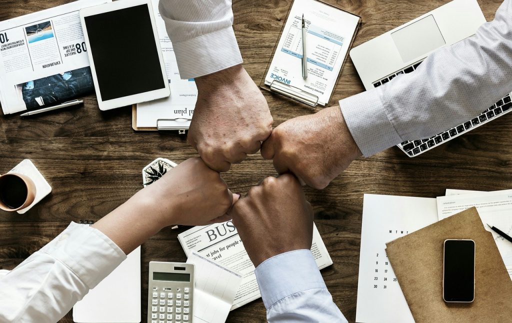 Business employees at at an office table fist bumping